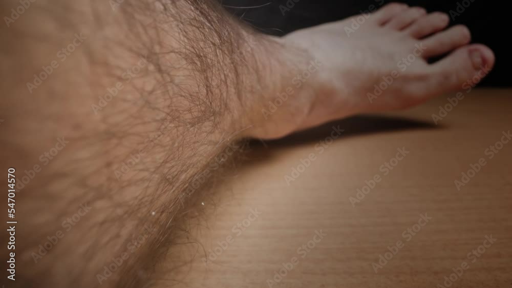 Skin surface with dark hair growing on ankle and calf of male leg lying on wooden surface in illuminated studio extreme closeup push in Skin surface with dark hair growing on ankle and calf of male leg lying on wooden surface in illuminated studio extreme closeup push in