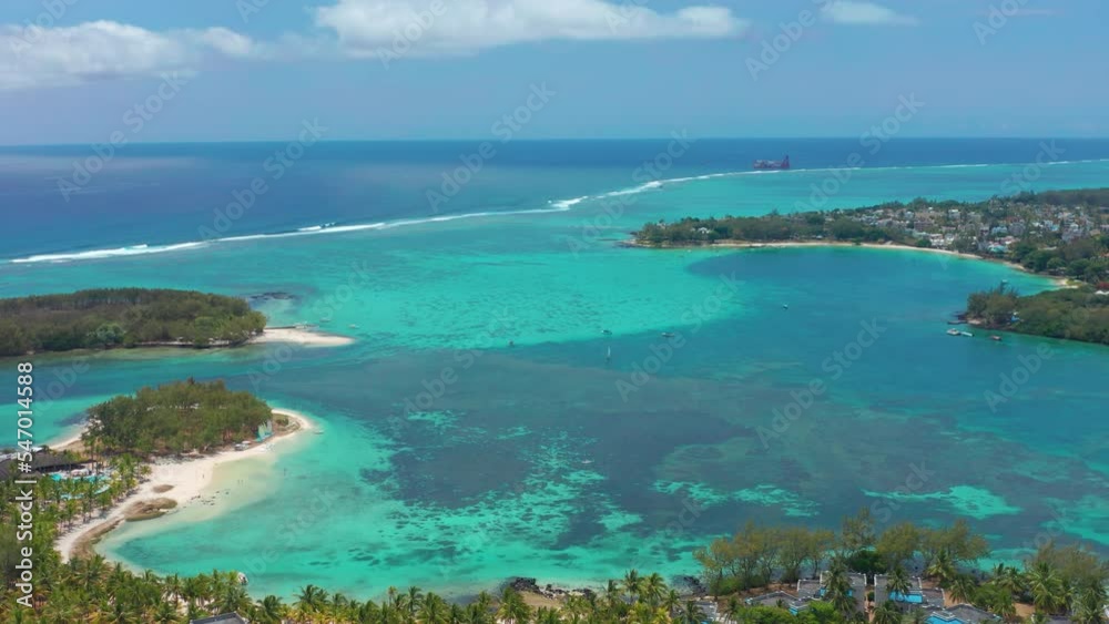Drone flight over the blue lagoon in the Indian Ocean on the island of Mauritius with turquoise water, green palm trees. The dream of tourists from all over the world. Vacation and travel concept
