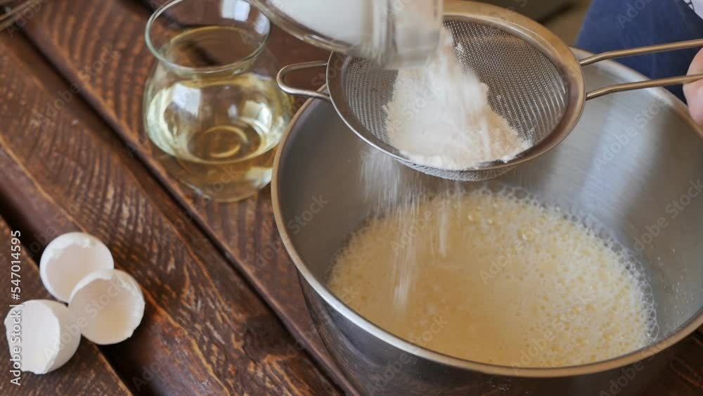 Pour wheat flour into a metal sieve to sift into a mixture of batter ingredients in a deep metal bowl. Cooking cupcakes Pour wheat flour into a metal sieve to sift into a mixture of batter ingredients in a deep metal bowl. Cooking cupcakes