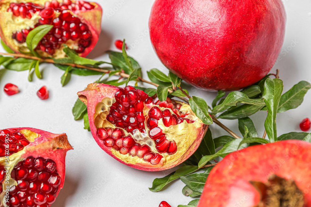 Fresh pomegranates and plant branches on white background, closeup Fresh pomegranates and plant branches on white background, closeup