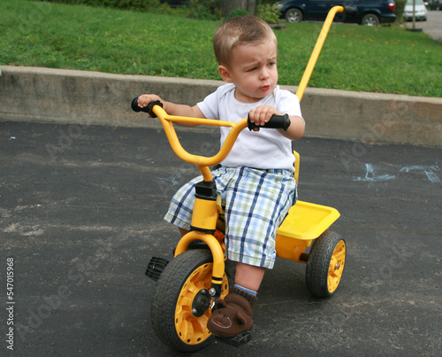 Young toddler boy  pedalling on a yellow tricycle