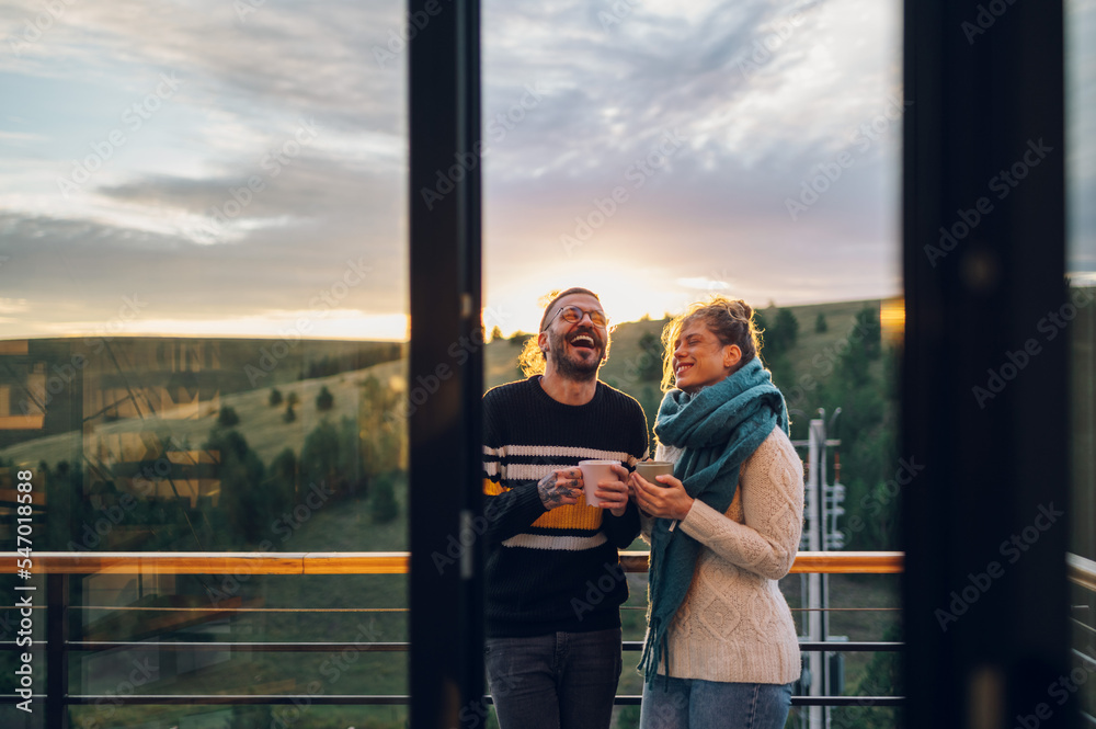 Young couple drinking coffee or tea while standing on their balcony at