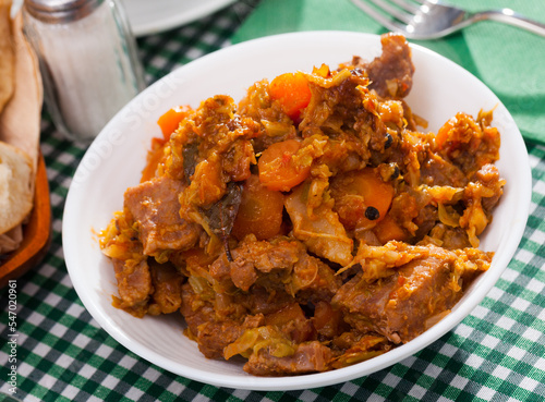 Juicy pork with stewed cabbage and carrot on plate
