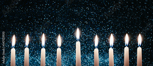 Hanukkah candles. Traditional candelabrum with burning candles on black background. Celebrating religious Jewish holiday.