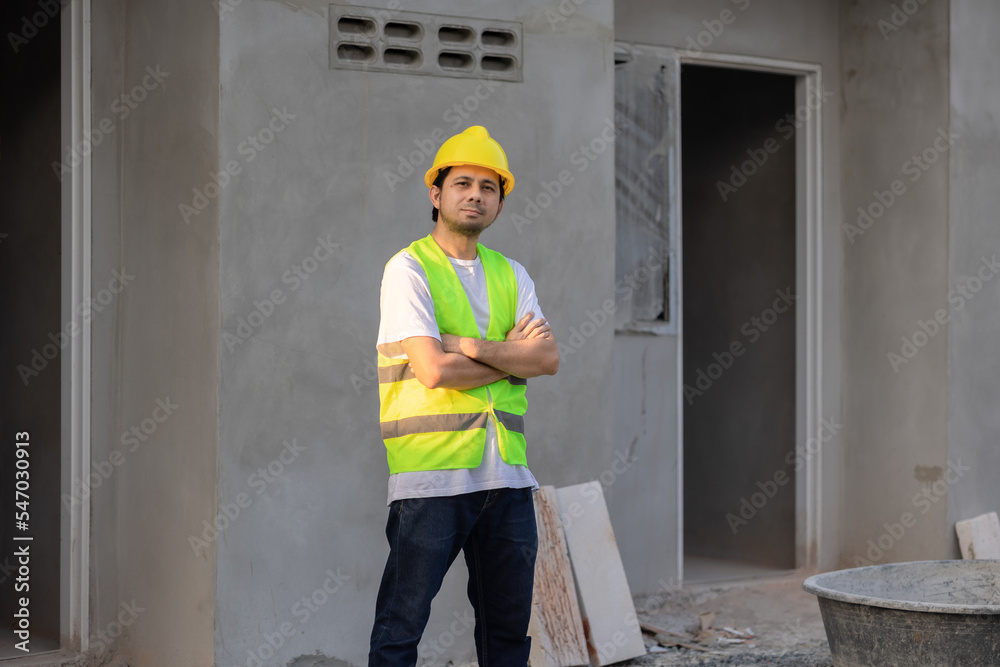 Portrait of an Asian male construction worker confidently standing with his arms crossed looking at the camera at the construction site. Portrait of an Asian male construction worker confidently standing with his arms crossed looking at the camera at the construction site.