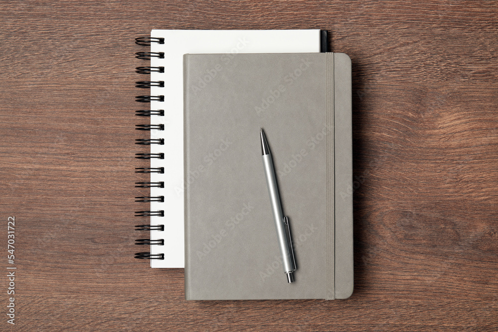 Stylish notebooks and pen on wooden table, top view Stylish notebooks and pen on wooden table, top view