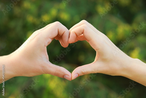 Couple making heart with hands outdoors on sunny day, closeup © New Africa