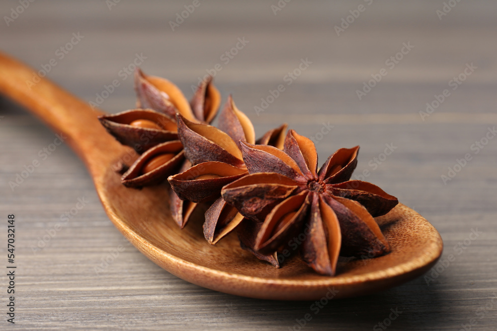 Spoon with aromatic anise stars on wooden table, closeup Spoon with aromatic anise stars on wooden table, closeup