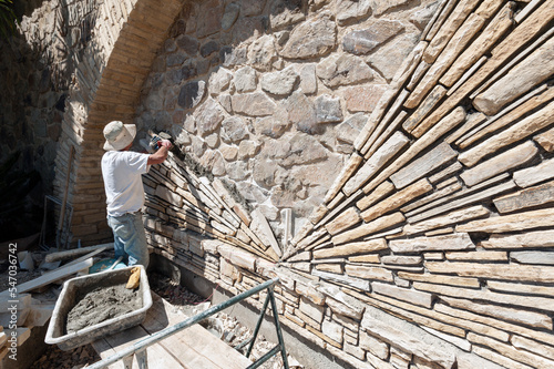 Bilde på lerret Stone mason installing hand cut stone in a radial pattern on an existing rock wa