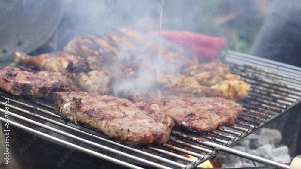 Grilled hot juicy fried pepper steak with smoke and a trickle of water pouring down on it in the backyard of a house, close-up side view in slow motion with zoom out. Grilled hot juicy fried pepper steak with smoke and a trickle of water pouring down on it in the backyard of a house, close-up side view in slow motion with zoom out.