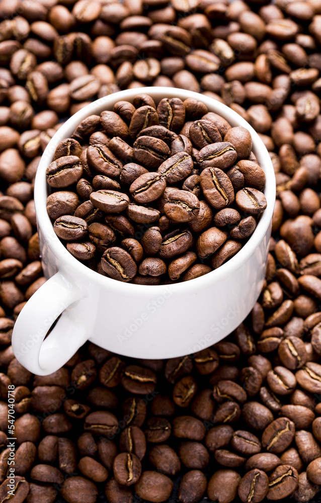 Fototapeta premium Roasted coffee beans in a cup, on dark background, close-up image, space for text