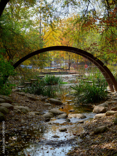 A bridge of steps holded on chains over a stream in a park