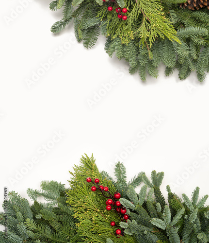 Holiday background with fresh festive garland of fir, spruce, pine, berries, and pinecones with white copy space