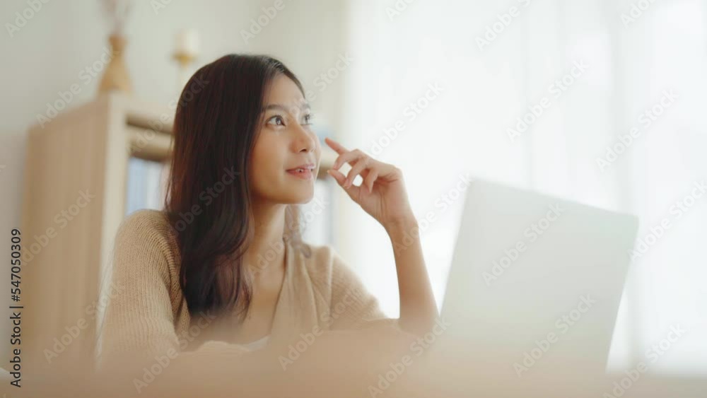 Young asian woman working on computer laptop on desk in living room at home Young asian woman working on computer laptop on desk in living room at home