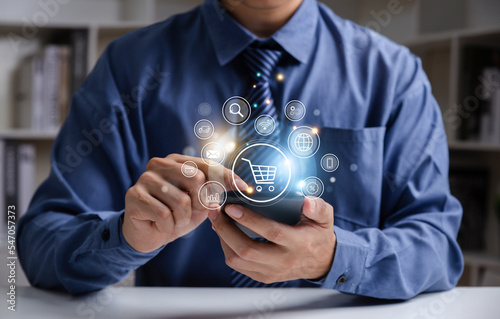 Young man using smartphone with shopping cart icon,  Online shopping and product procurement management concept.