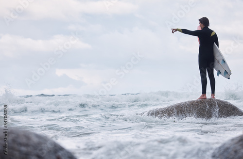 Man  pointing or surfer on rocks at beach  ocean or rough sea and watching tide  waves or water movement in Hawaii. Sports athlete  surf board or surfing person in fitness  workout or nature training