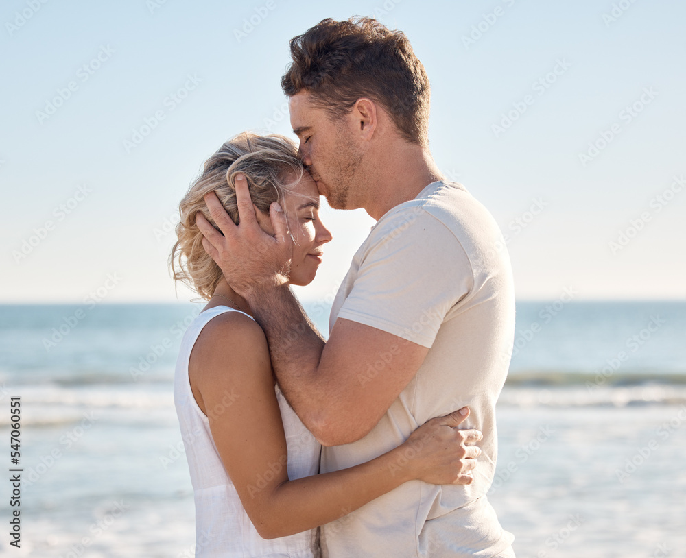 Couple, love and forehead kiss on beach by ocean, sea or Hawaii water waves in trust, love and security. Smile, happy or bonding woman and man on anniversary summer break in tropical nature location Couple, love and forehead kiss on beach by ocean, sea or Hawaii water waves in trust, love and security. Smile, happy or bonding woman and man on anniversary summer break in tropical nature location