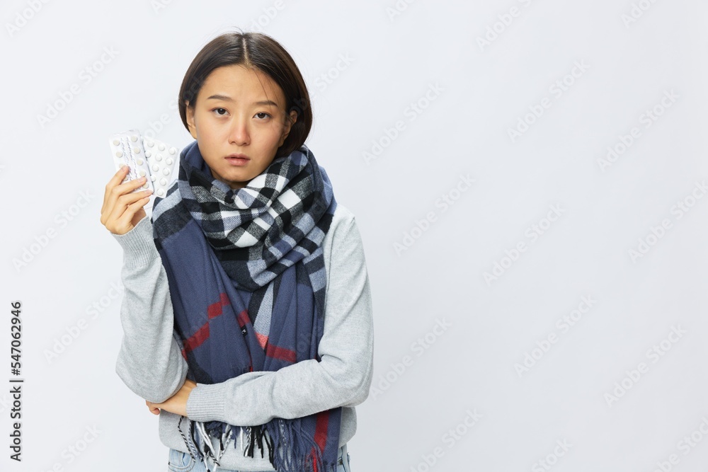 Asian woman headache cold flu holding medicine and pills in checkered plaid with fever sick of virus on white background, copy space Asian woman headache cold flu holding medicine and pills in checkered plaid with fever sick of virus on white background, copy space