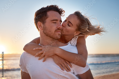 Love, couple and cheek kiss at beach on date, vacation or summer trip. Sunset, affection or romance of man and woman kissing at seashore, bonding and enjoying quality time together outdoors at coast.