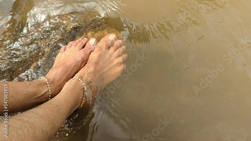 feet of a woman with anklets being washed by flowing water in a river stream 