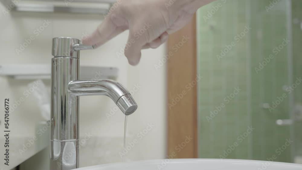 The faucet in the bathroom with running water. Man keeps turning off the water to save water energy and protect the environment. save water concept The faucet in the bathroom with running water. Man keeps turning off the water to save water energy and protect the environment. save water concept