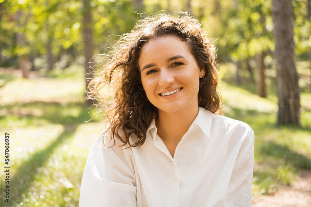 Close up portrait of young cheerful woman smiling and looking at camera outdoor in forest Close up portrait of young cheerful woman smiling and looking at camera outdoor in forest