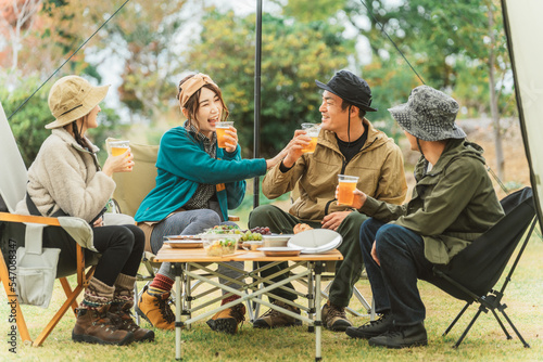 キャンプ場で仲間と一緒に楽しくビールを飲んでパーティーするアジア人の男女 