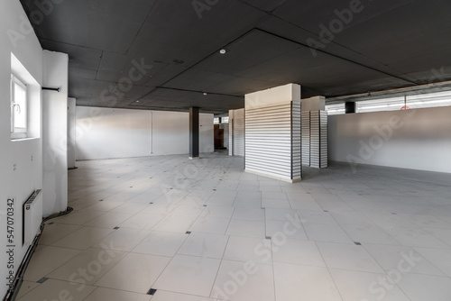 Empty retail space with a black ceiling and a dirty floor, immediately after repair