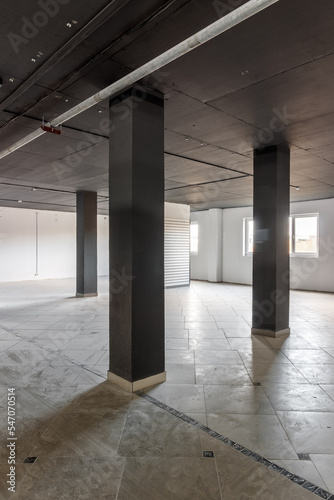 Empty retail space with a black ceiling and a dirty floor, immediately after repair