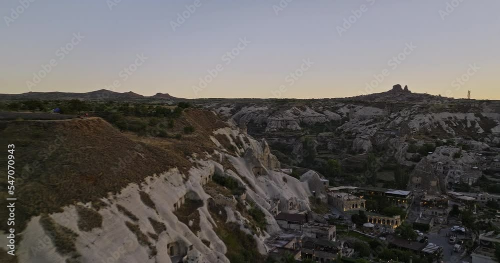 Göreme Turkey Aerial v31 low level flyover high plateau view point capturing ancient town surrounded by landscape of rock formations with sun setting at horizon - Shot with Mavic 3 Cine - July 2022 Göreme Turkey Aerial v31 low level flyover high plateau view point capturing ancient town surrounded by landscape of rock formations with sun setting at horizon - Shot with Mavic 3 Cine - July 2022