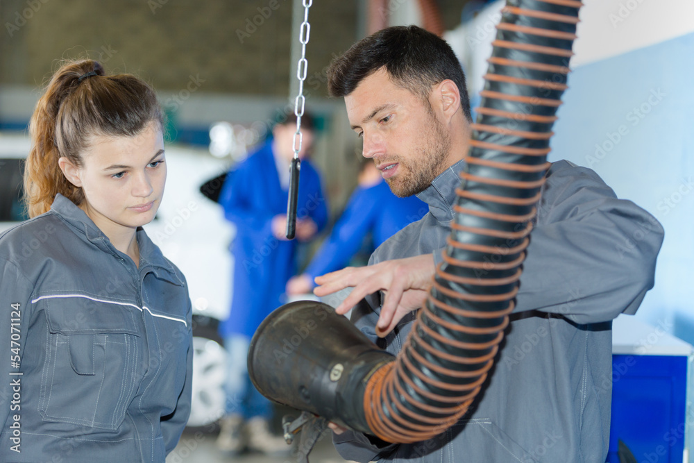 Obraz premium mechanic showing female apprentice an extraction hose