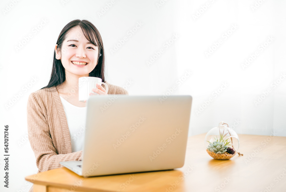 家でコーヒーを飲みながらノートパソコンを使う笑顔のアジア人女性
家でコーヒーを飲みながらノートパソコンを使う笑顔のアジア人女性