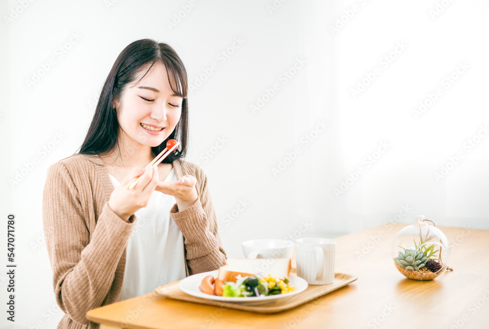 朝食で美味しそうに笑顔でトーストされた食パンを食べる日本人女性
