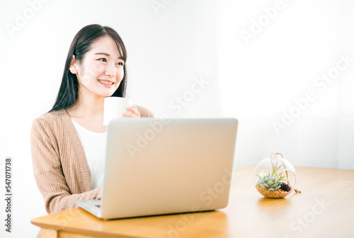家でノートパソコンを使って映画や動画・ネットショッピングを楽しむアジア人女性  © buritora