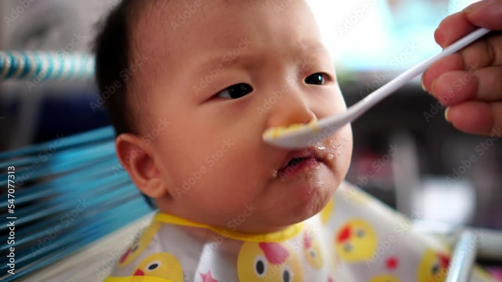 Grandmother feed baby porridge while watch television Grandmother feed baby porridge while watch television