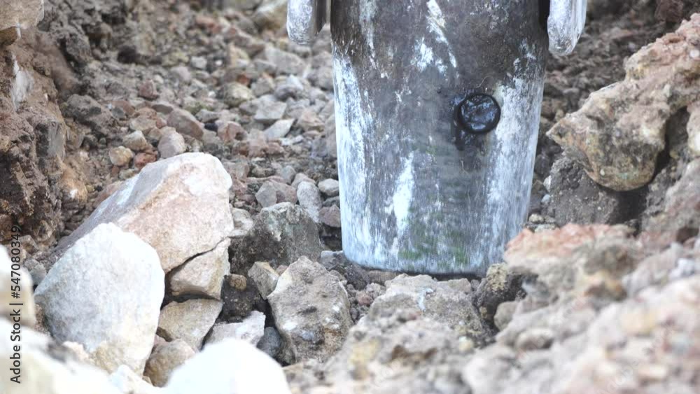 Loud destruction of solid soil rock with pneumatic jackhammer excavator