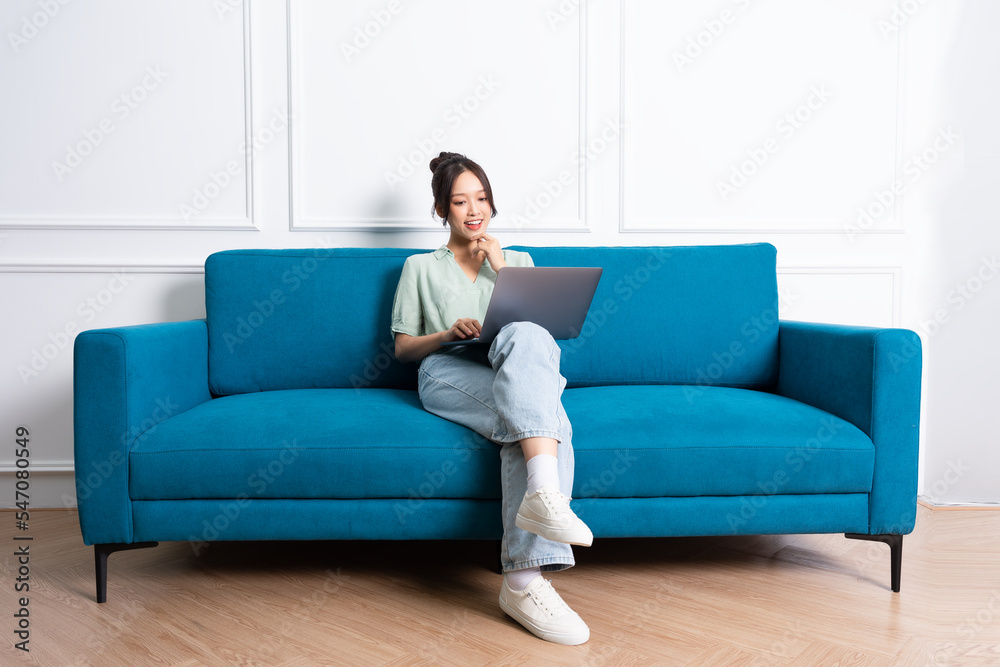 image of young Asian girl sitting on sofa at home image of young Asian girl sitting on sofa at home