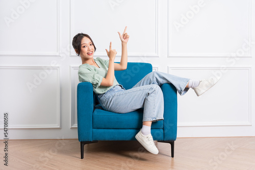 image of young Asian girl sitting on sofa at home