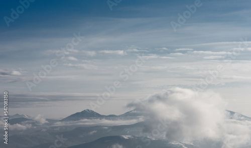 The mountain range covered with snow and surrounded by clouds. Winter mountain landscape. © Oleksiy