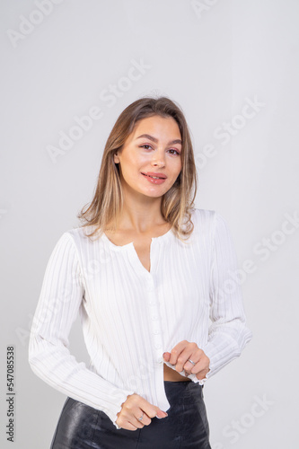 Portrait of a beautiful young brown-haired girl in a white knitted sweater on a white background/ Model smiling and lookind forward