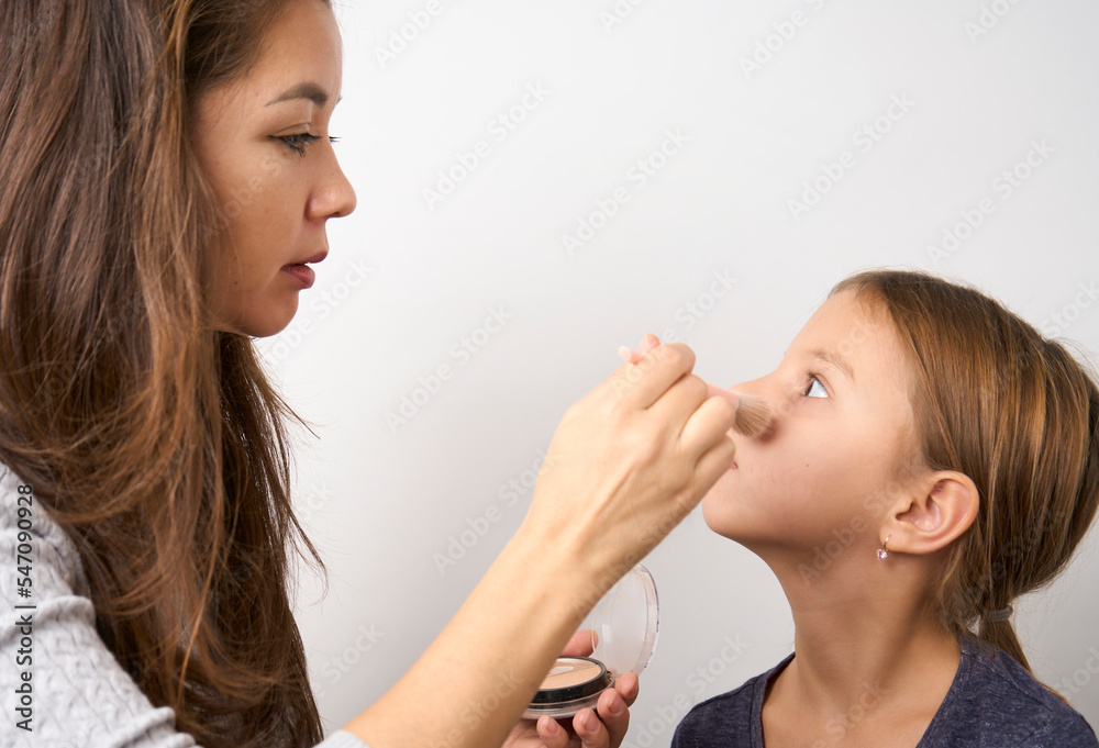 Little girl applying makeup, white background