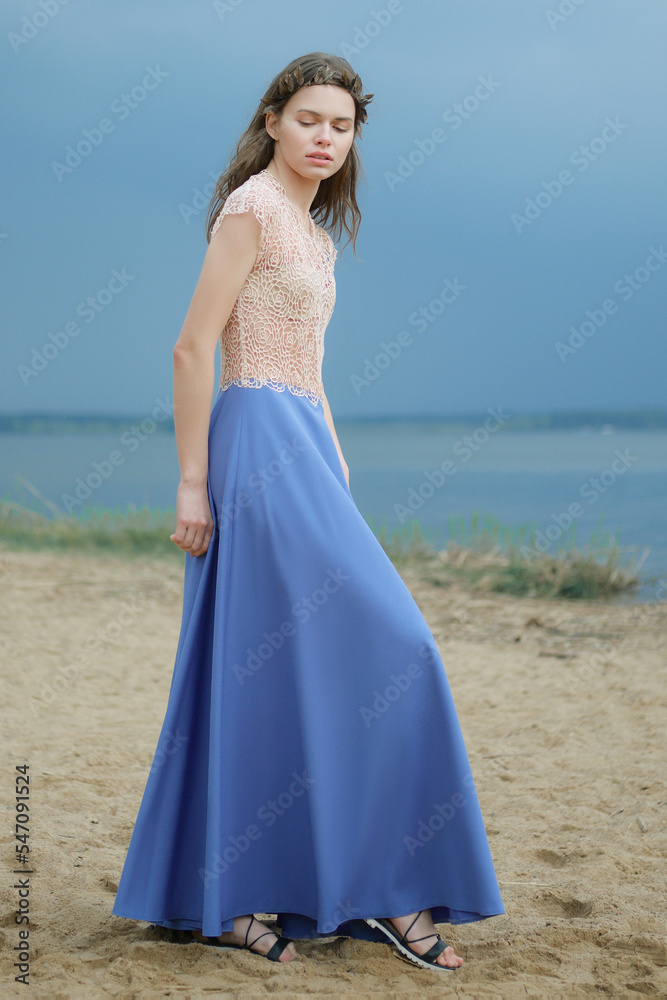 Dreamy woman in long blue skirt and lace blouse on the beach