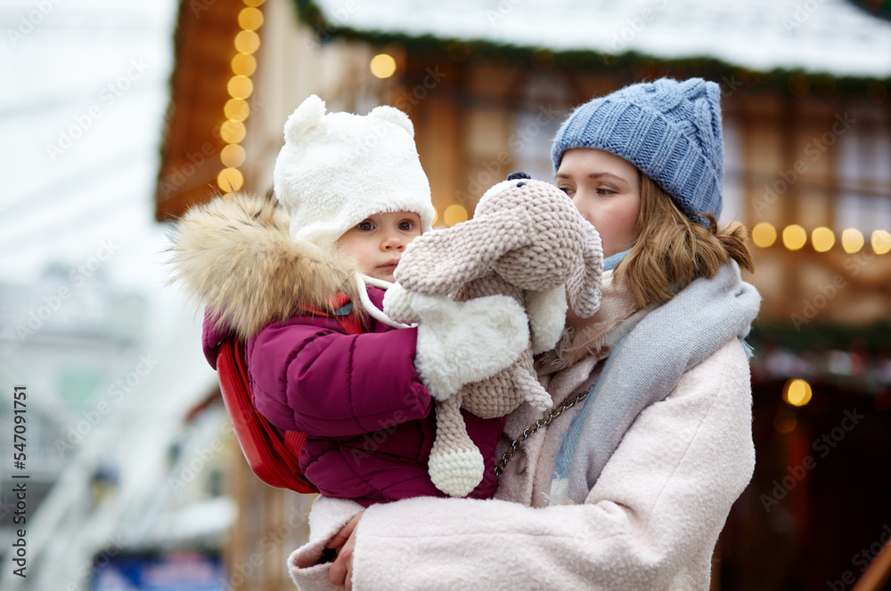Mother and daughter are walking around the city on Christmas and New Year holidays. Parent and little child having fun outdoors Mother and daughter are walking around the city on Christmas and New Year holidays. Parent and little child having fun outdoors