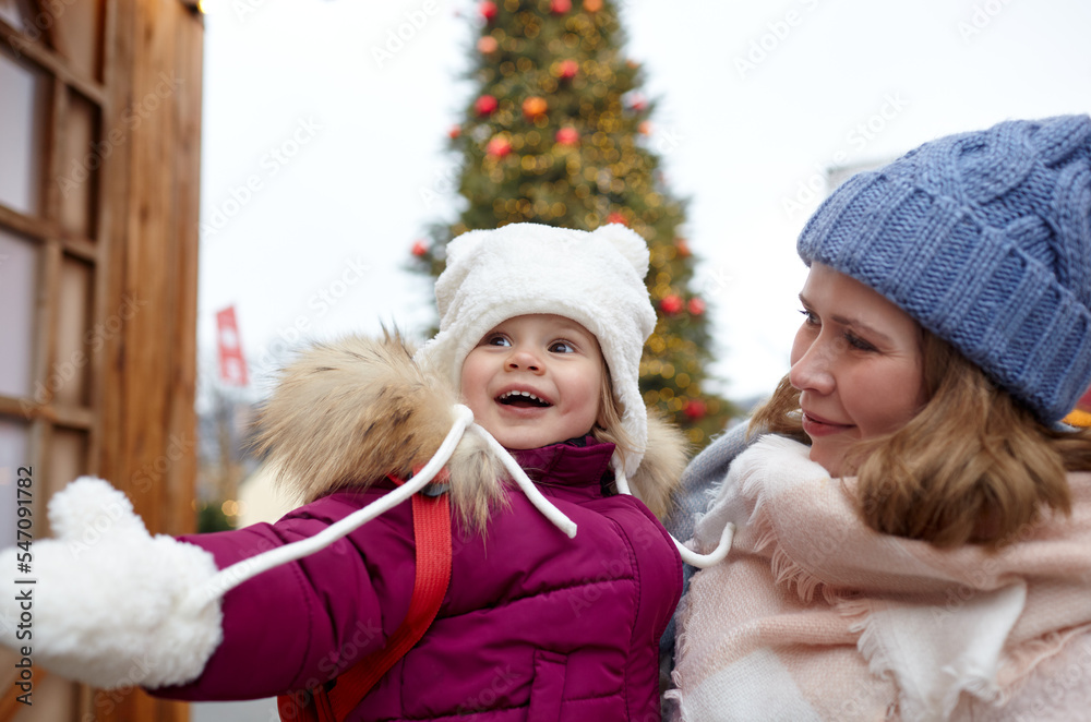 Obraz premium Mother and daughter are walking around the city on Christmas and New Year holidays. Portrait of happy mother and daughter having fun in the street