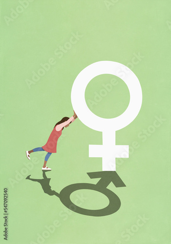 Woman pushing female gender symbol with male gender shadow
 photo