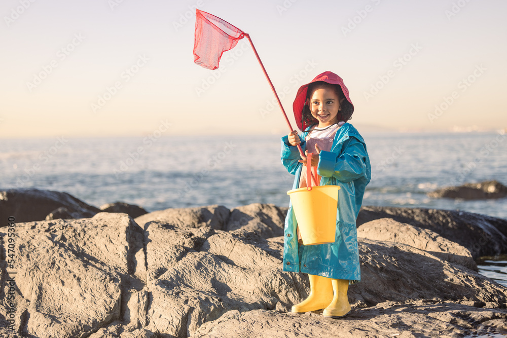 Child, girl or kid fishing net or bucket by beach rock pools, ocean or sea  for