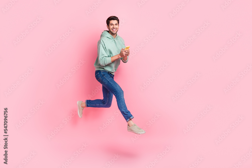 Full length photo of cheerful boy addicted user wear stylish outfit go empty space hurry device shop sale isolated on pink color background