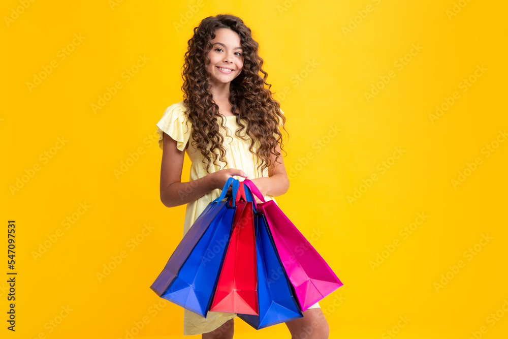 Girl teenager with shopping bags isolated on yellow backgound. Shopping and sale concept. Happy teenager portrait. Smiling girl.