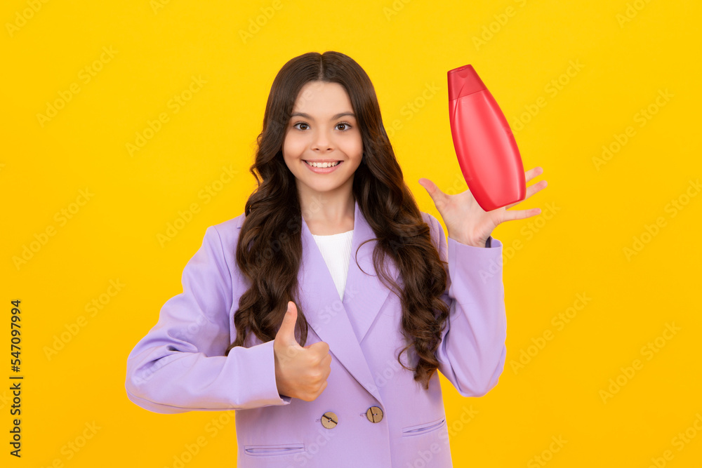 Teenager child girl showing bottle shampoo conditioners or shower gel isolated on yellow background. Hair cosmetic product. Mock up bottle. Happy teenager, smiling emotions of teen girl. Teenager child girl showing bottle shampoo conditioners or shower gel isolated on yellow background. Hair cosmetic product. Mock up bottle. Happy teenager, smiling emotions of teen girl.