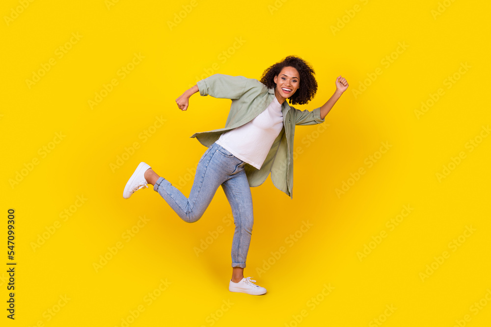 Full body photo of funny young woman curly hair running fast hobby free time wear trendy khaki outfit isolated on yellow color background